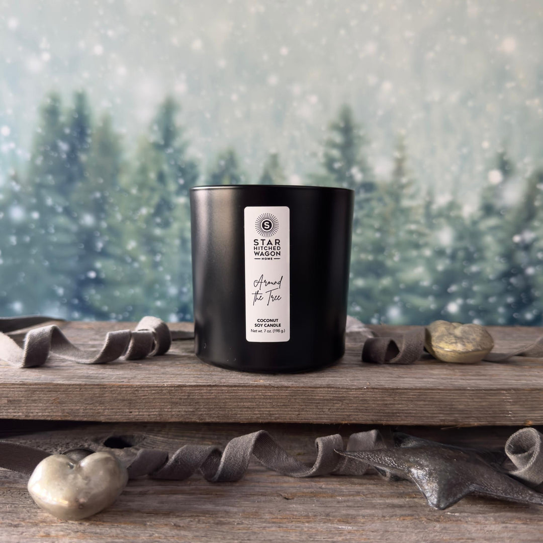 Black candle with a label on a wooden surface with a snowy forest background