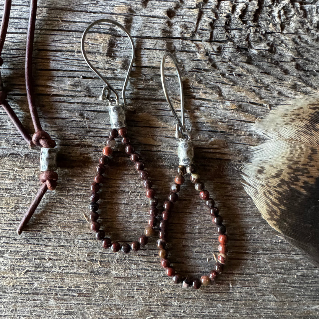 Jasper beaded earrings on a wooden surface with feather.