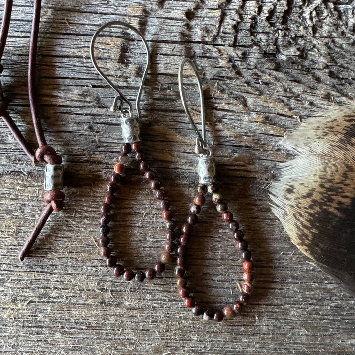 Jasper beaded earrings on a wooden surface with feather.