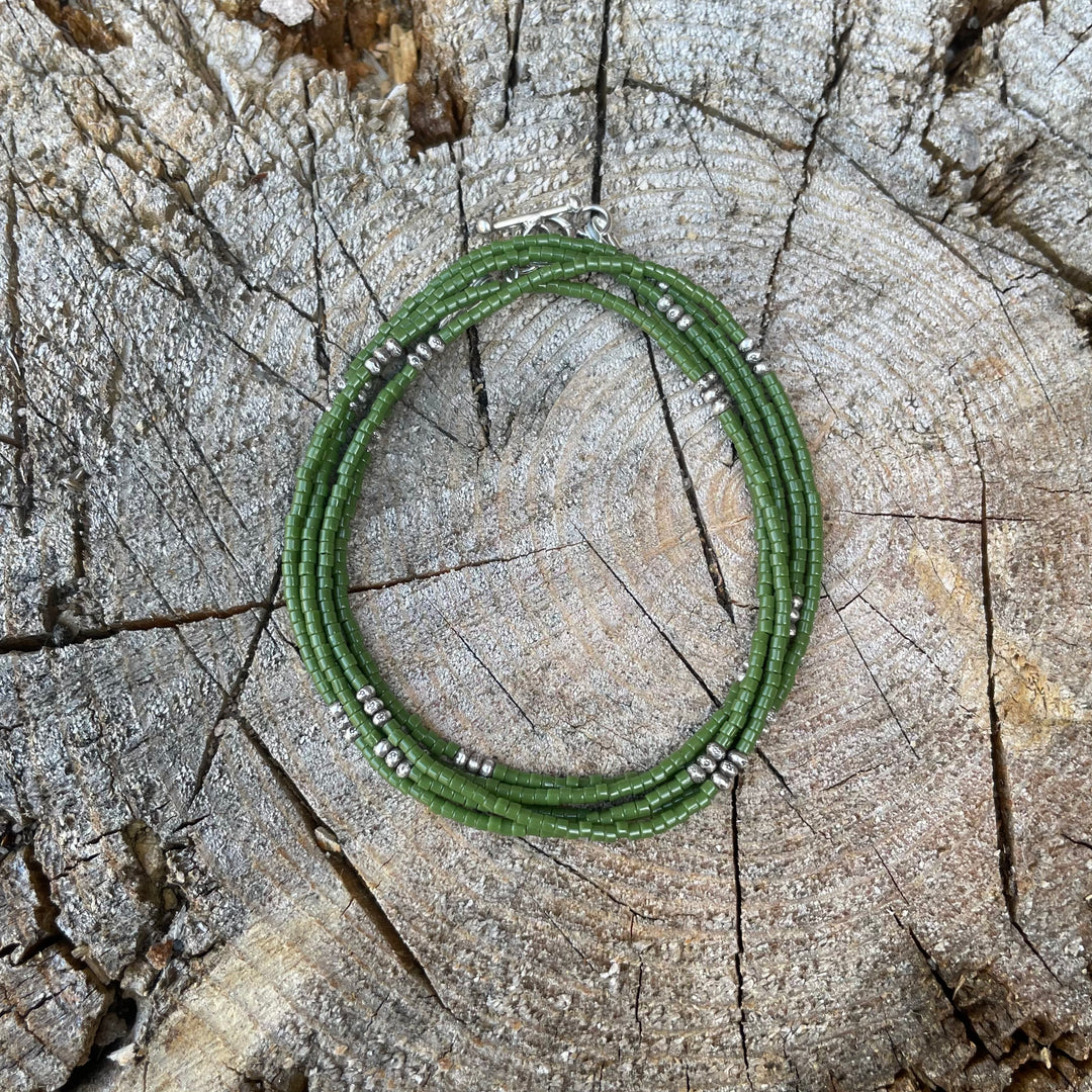 Green seed bead wrap bracelet on a wooden surface