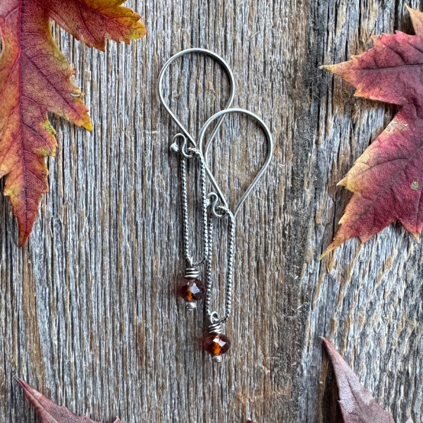 Harvest Glow -  Spessartite Garnet and Silver Earring surrounded by fall leaves on wooden backdrop