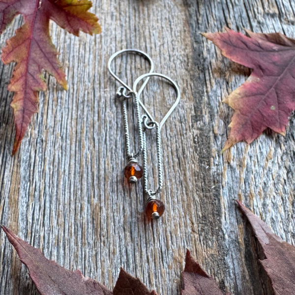 Harvest Glow -  Spessartite Garnet and Silver Earring surrounded by fall leaves on wooden backdrop