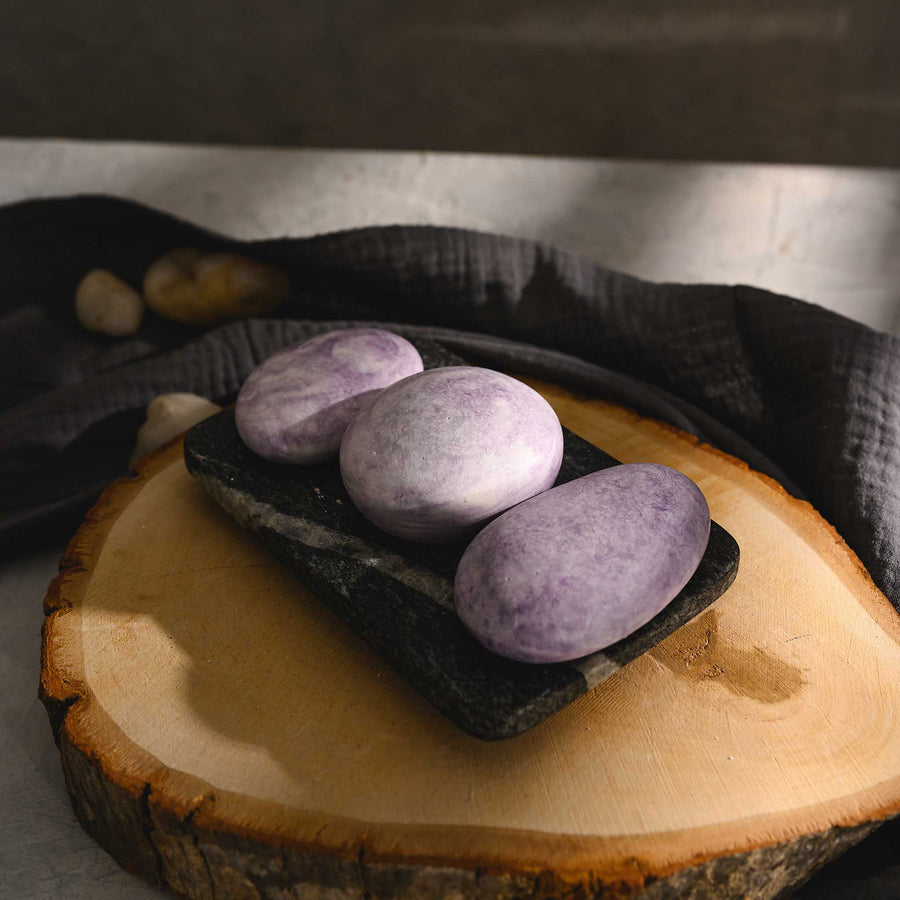 Jane River Stone Salt Soap Trio in black soap dish on wood slab.