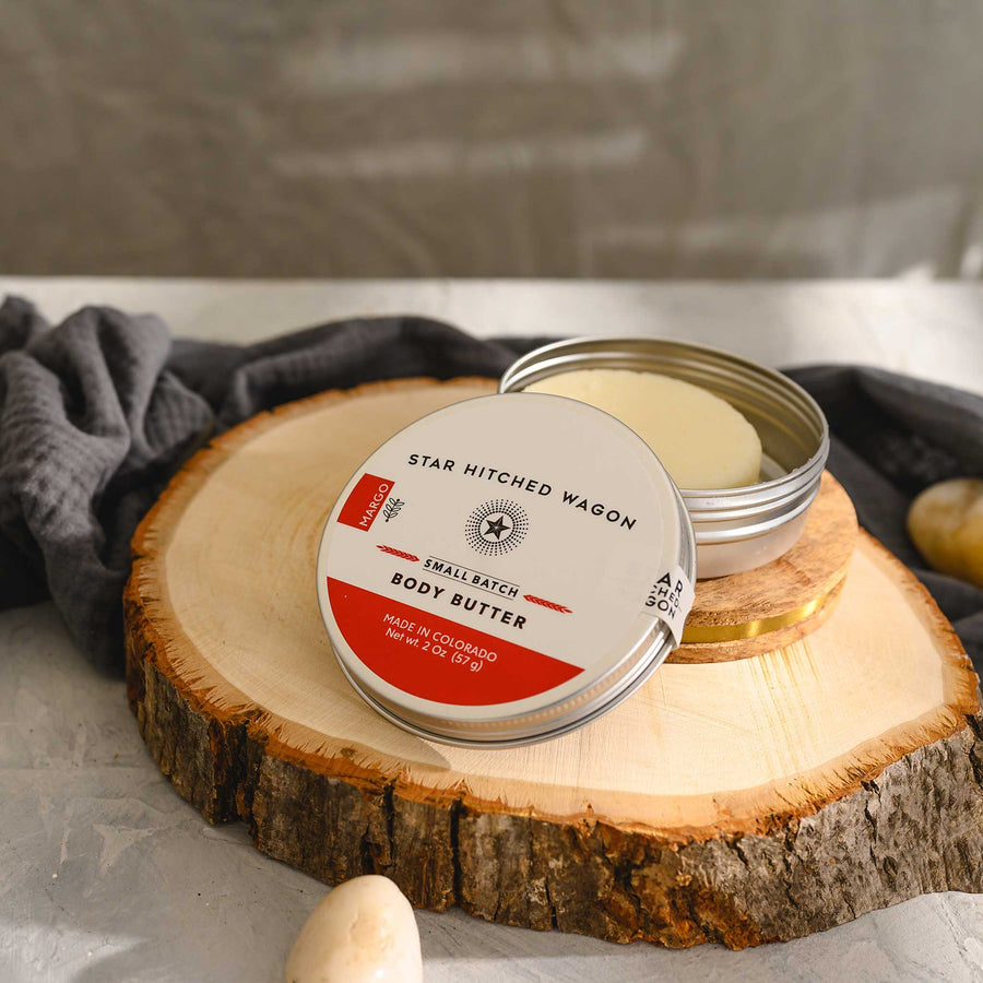 Margo body butter moisturizer in reusable tin, handcrafted with rich oils and butters to soothe dry skin. Scented with citrus, herbs, and spruce.