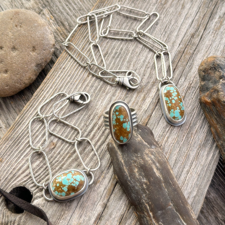 Number 8 Turquoise Ring, Necklace and Bracelet on wooden background with rocks and leather lace.