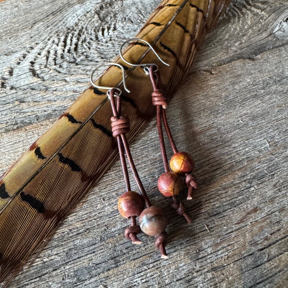 Jasper and leather earrings on a wood background with feather.