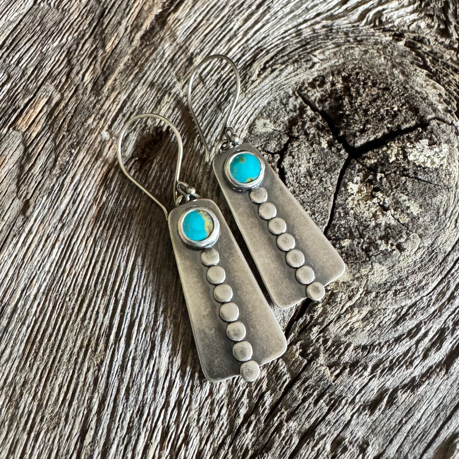 Royston turquoise and silver earrings with round turquoise stones, hand-applied sterling silver disc accents, and French hook earwires on rustic wood backdrop