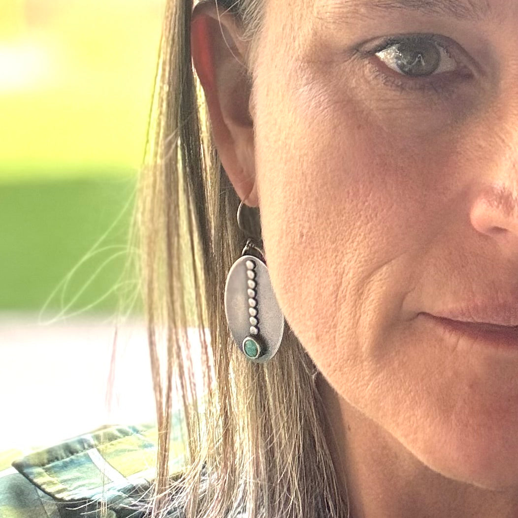 Close-up of a woman wearing Sacred Path royston turquoise sterling silver and earrings with a blurred background