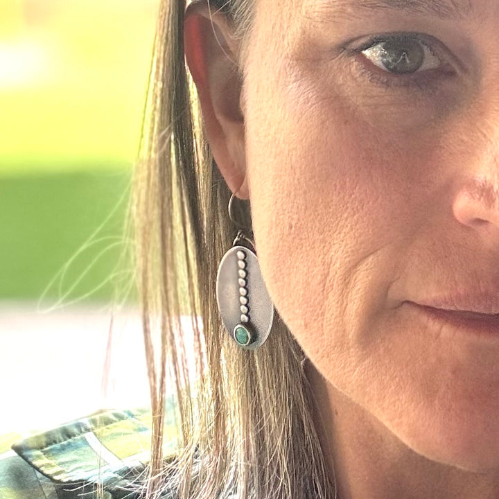 Close-up of a woman wearing Sacred Path royston turquoise sterling silver and earrings with a blurred background