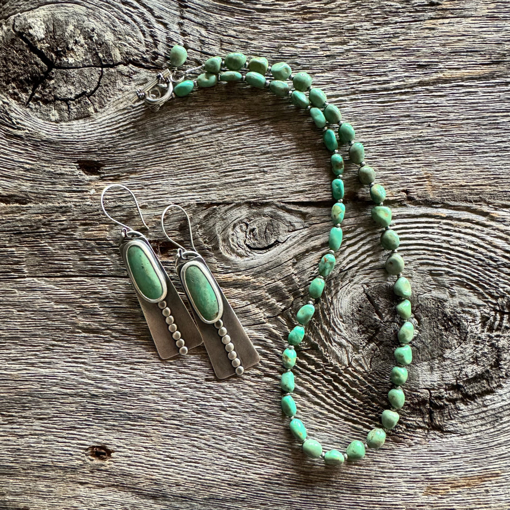 Elisa turquoise nugget necklace and Elisa turquoise and sterling silver earrings on a wooden surface