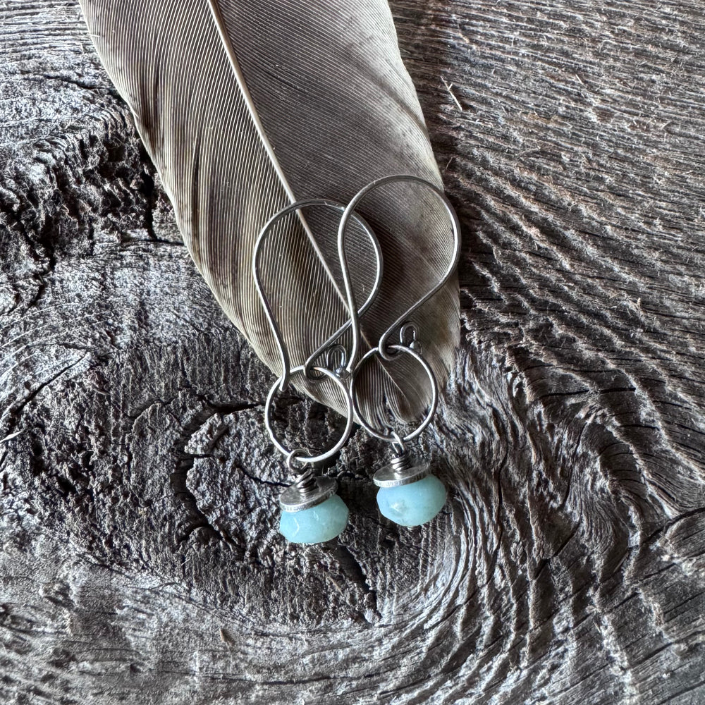 Amazonite and silver earrings on a wooden surface with feather