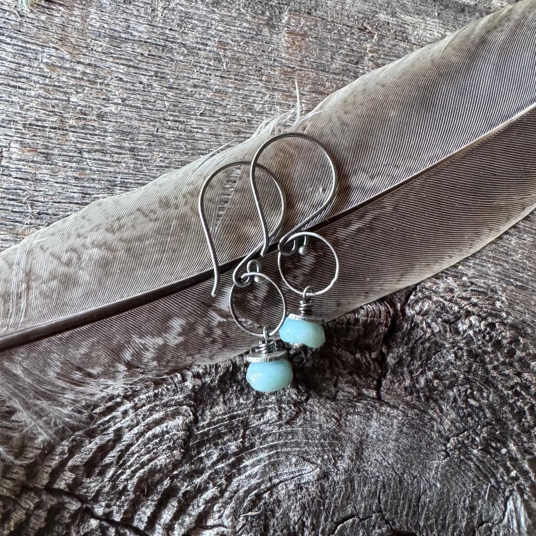Amazonite and silver earrings on a wooden surface with feather.