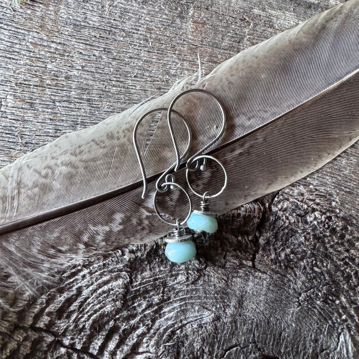 Amazonite and silver earrings on a wooden surface with feather.