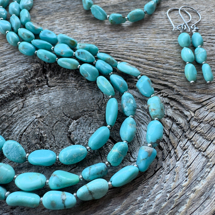 Campitos turquoise beaded jewelry set featuring three necklaces and matching drop earrings, displayed on a rustic weathered wood surface.