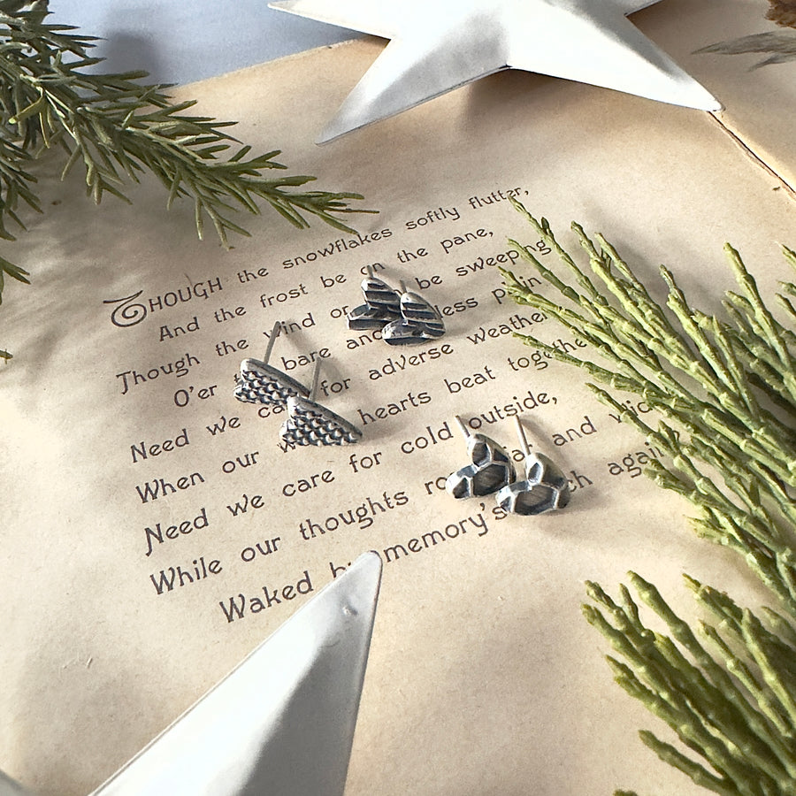 Silver heart earring trio on a piece of paper with text and greenery.