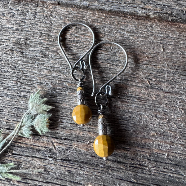 Pair of earrings with yellow mookaite and thai silver beads on a wooden surface with pressed flower