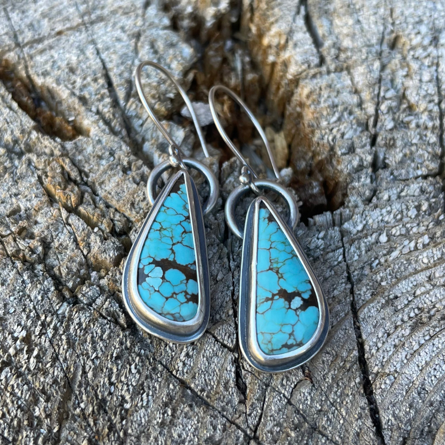 The Wayfinder Sterling Silver Turquoise Drop Earrings on rustic wood background.