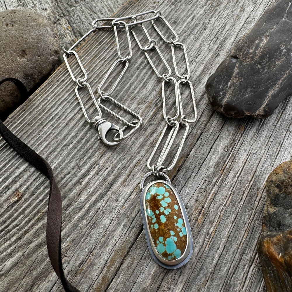 Sterling Silver and Turquoise Necklace with rocks and leather lace on wood surface.