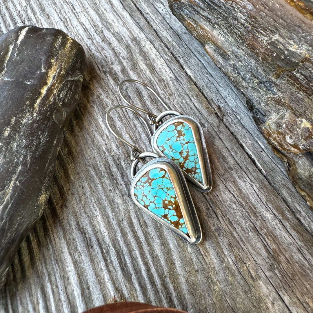 The Wayfinder Sterling Silver Turquoise Drop Earrings on rustic wood background.