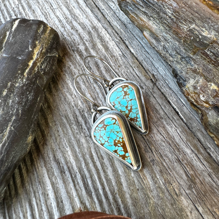 The Wayfinder Sterling Silver Turquoise Drop Earrings on rustic wood background.