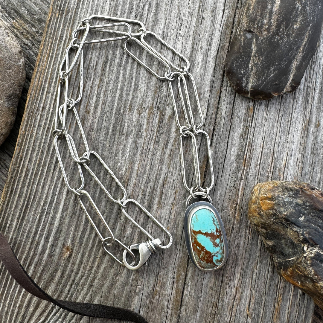Sterling Silver and Turquoise Necklace with rocks and leather on wood surface.
