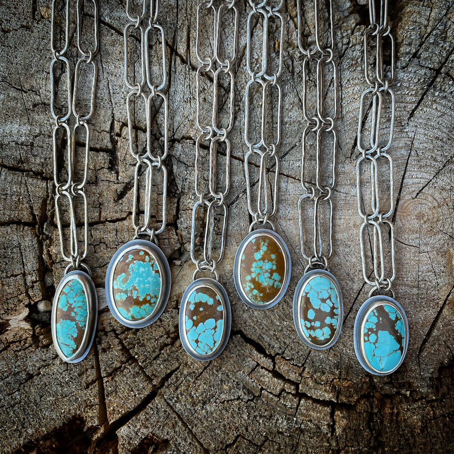 Sterling silver and turquoise necklace collection on wood surface.