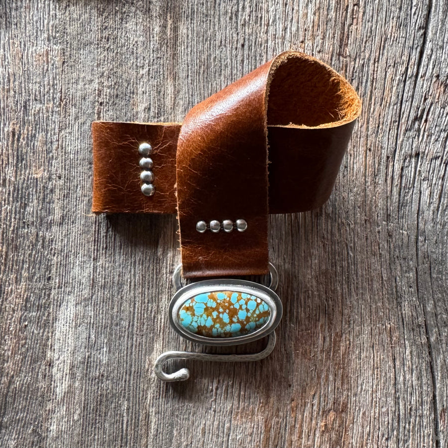 Turquoise and leather bracelet on a wooden surface